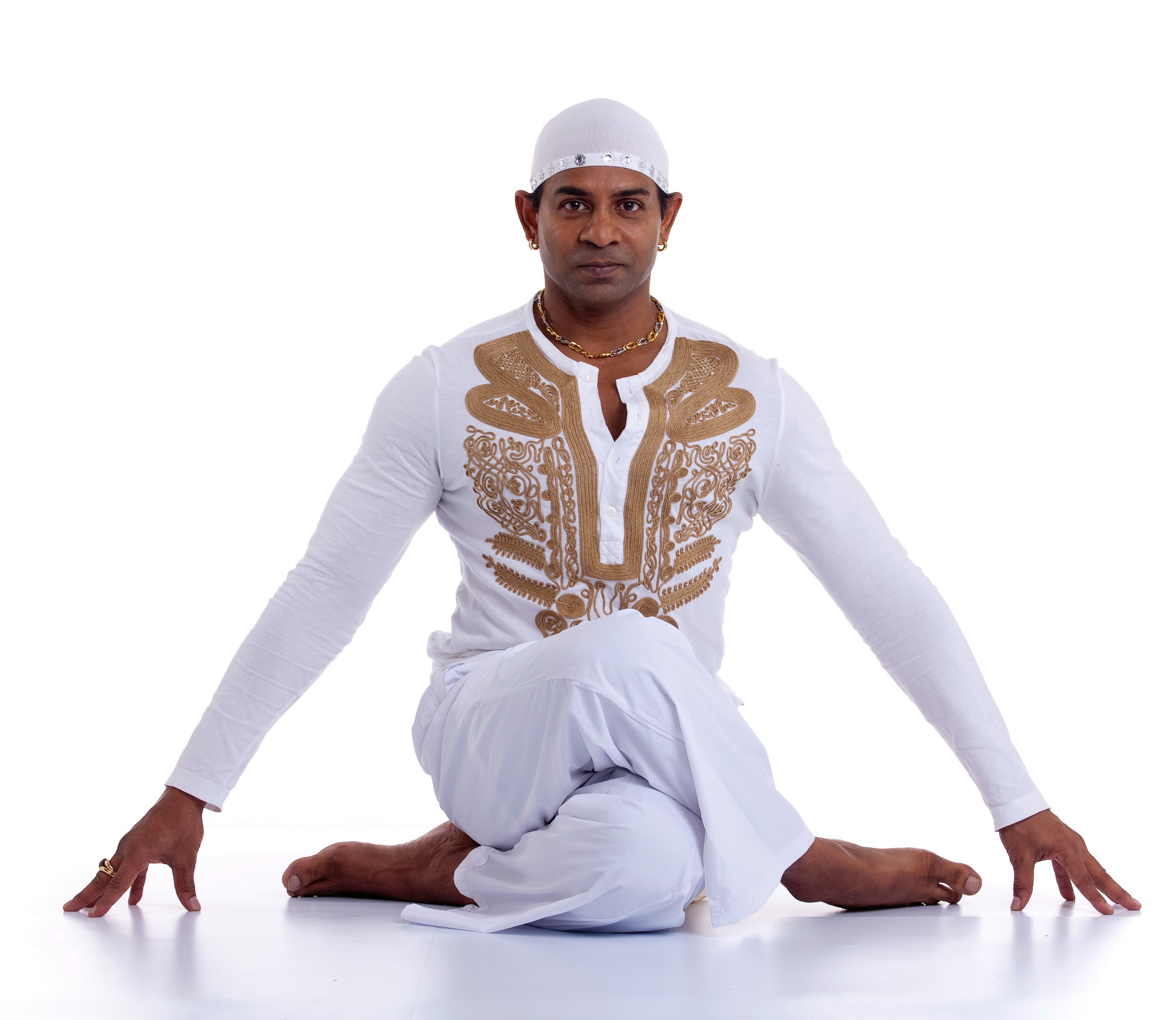 A man sitting on the ground in a white outfit
