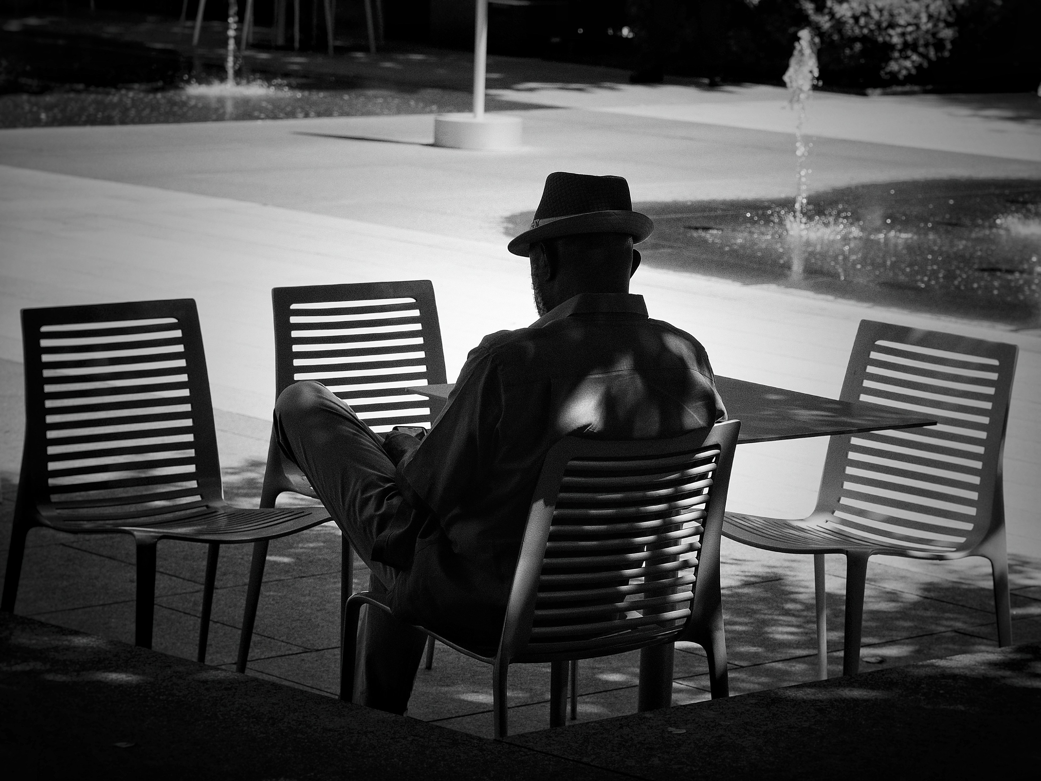 A man sitting on a bench in front of a fountain