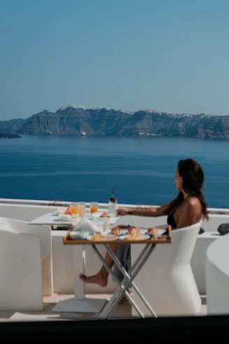 A woman sitting at a table with a view of the ocean