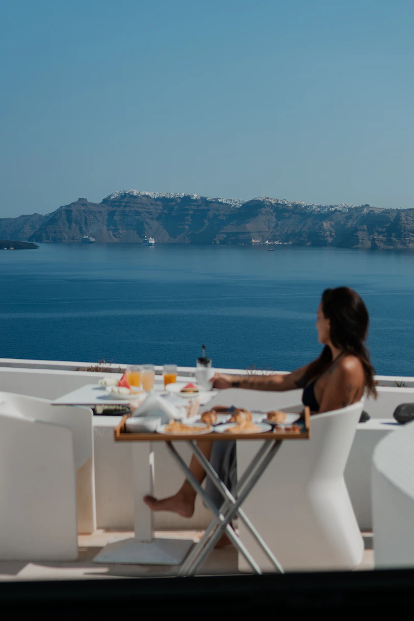 A woman sitting at a table with a view of the ocean