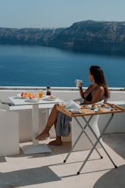 A woman sitting at a table with a view of the ocean