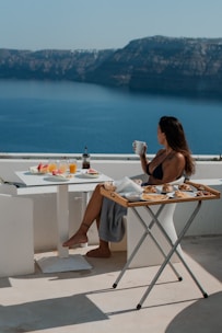 A woman sitting at a table with a view of the ocean