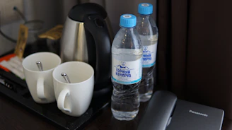 A tray with a cell phone, cups and a bottle of water