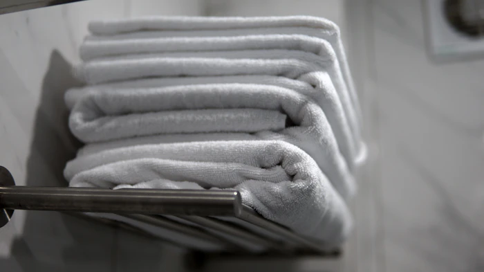 A neatly folded stack of handwoven cotton towels on a rack