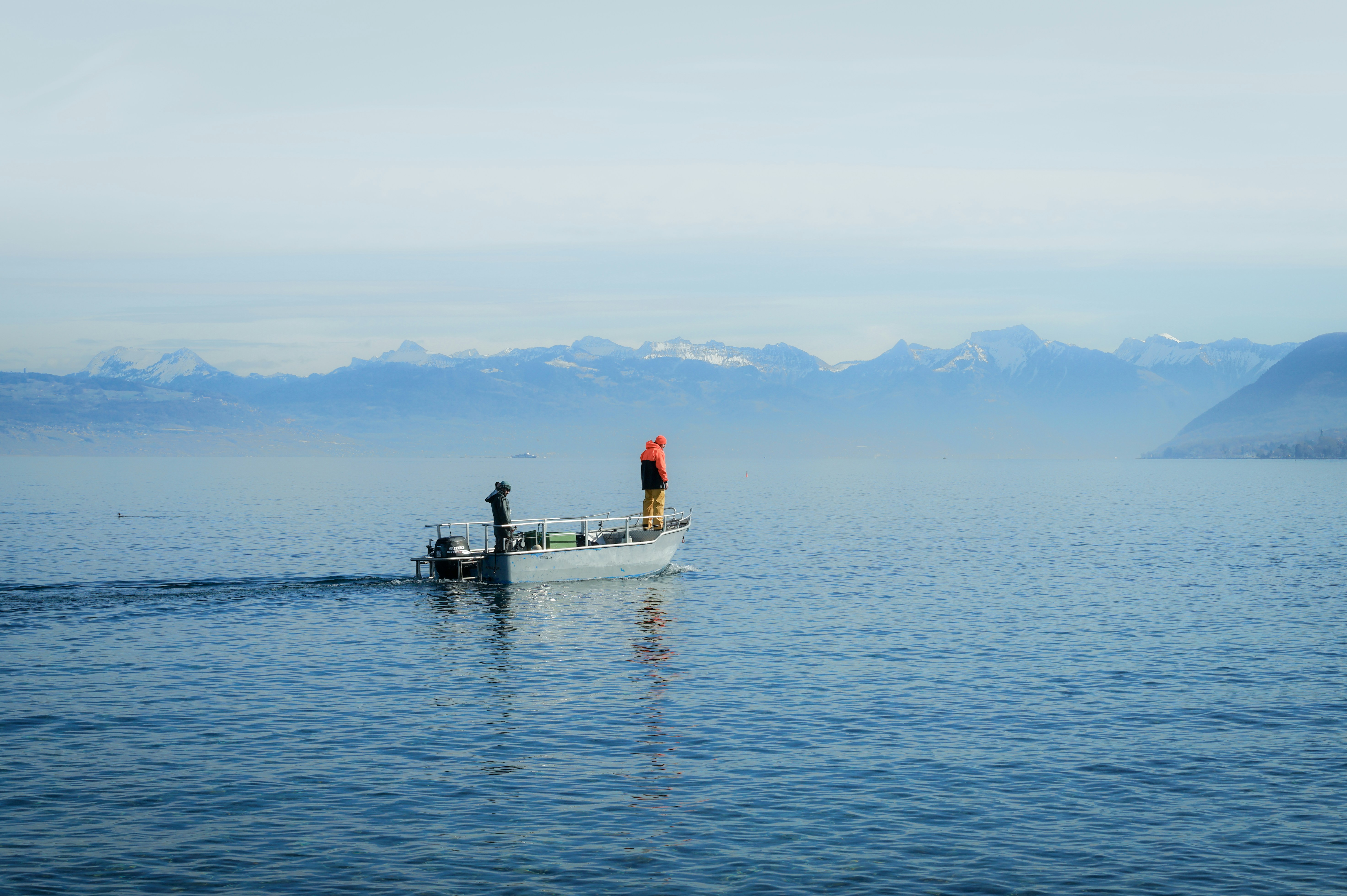A man standing on a boat in the middle of a lake