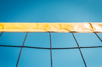 A close up of a volleyball net with a blue sky in the background