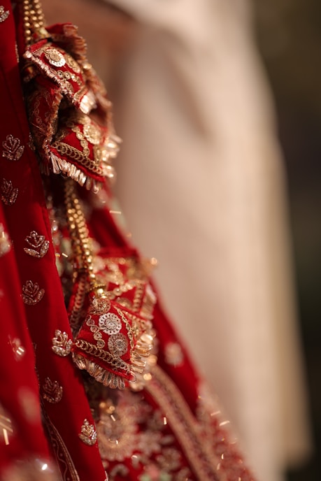 A close up of a bride's red and gold wedding dress