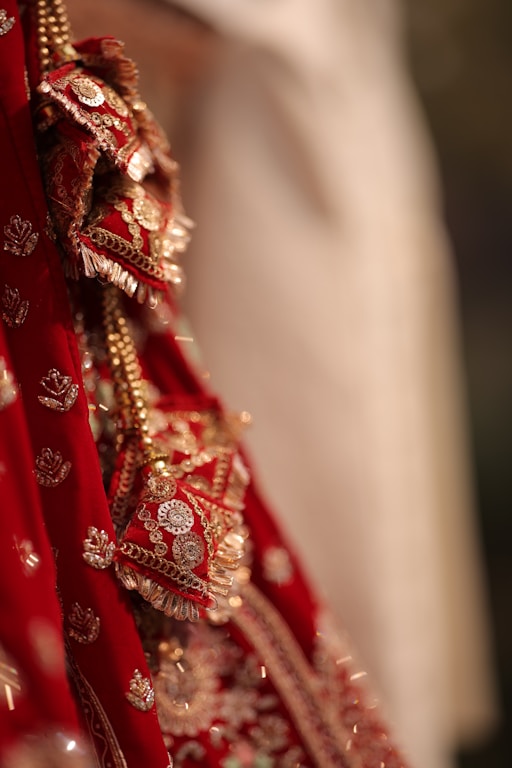 A close up of a bride's red and gold wedding dress