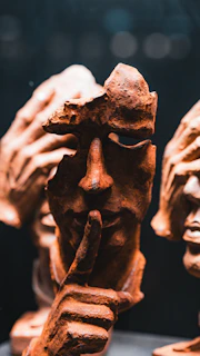 A close up of a statue of a person holding a finger to his mouth