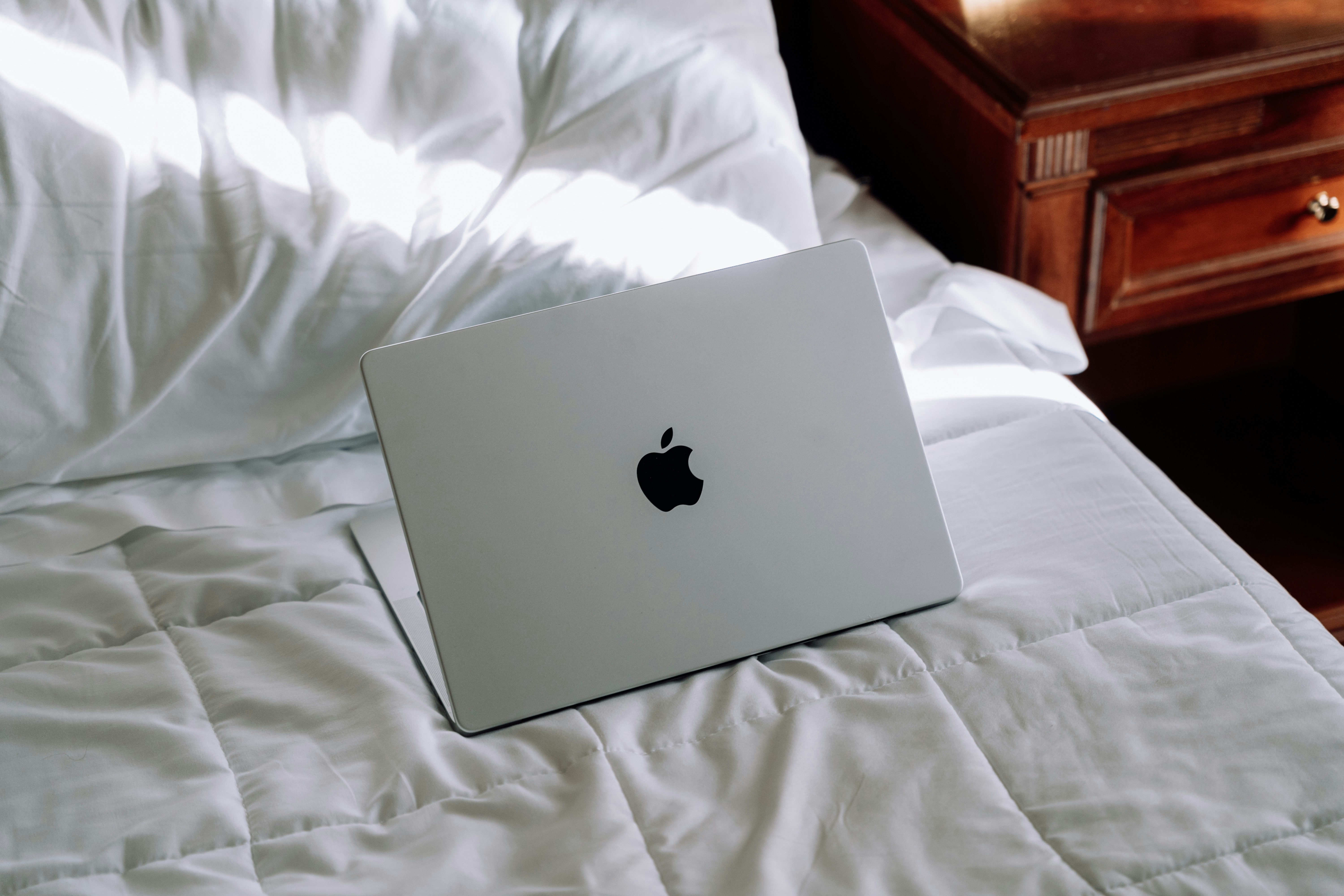 An apple laptop is sitting on a bed