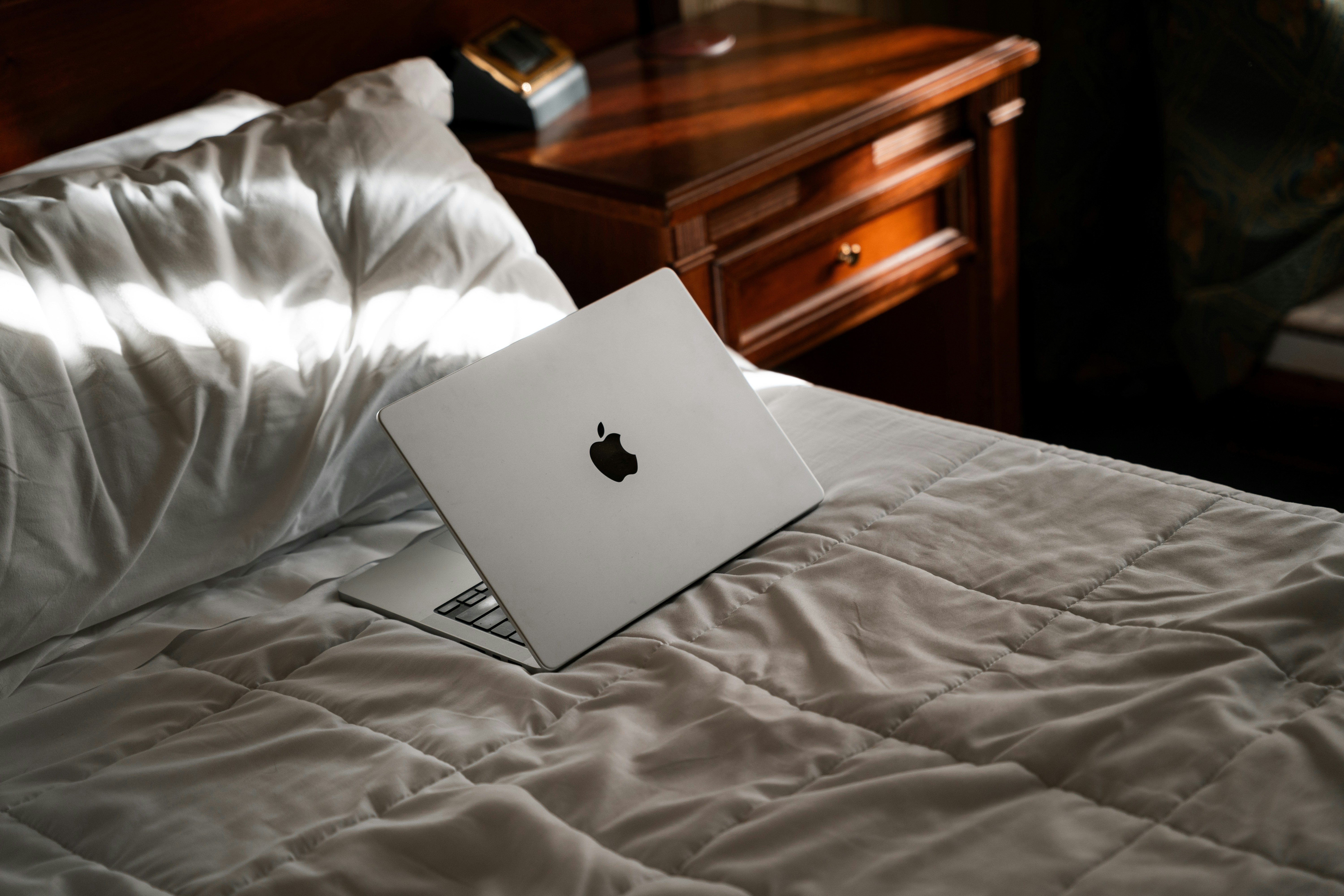 An apple laptop sitting on top of a bed