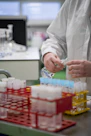 A person in a lab coat pouring liquid into a container