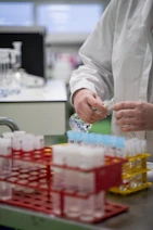A person in a lab coat pouring liquid into a container