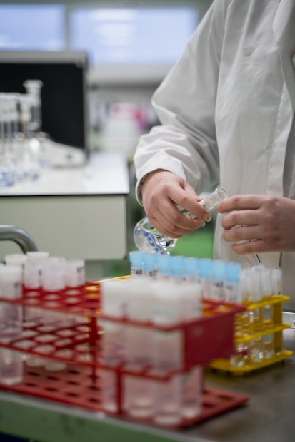 Gloved hands working with sample tubes above racks of colour coded tubes