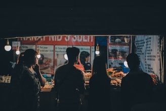 A group of people standing around a food stand