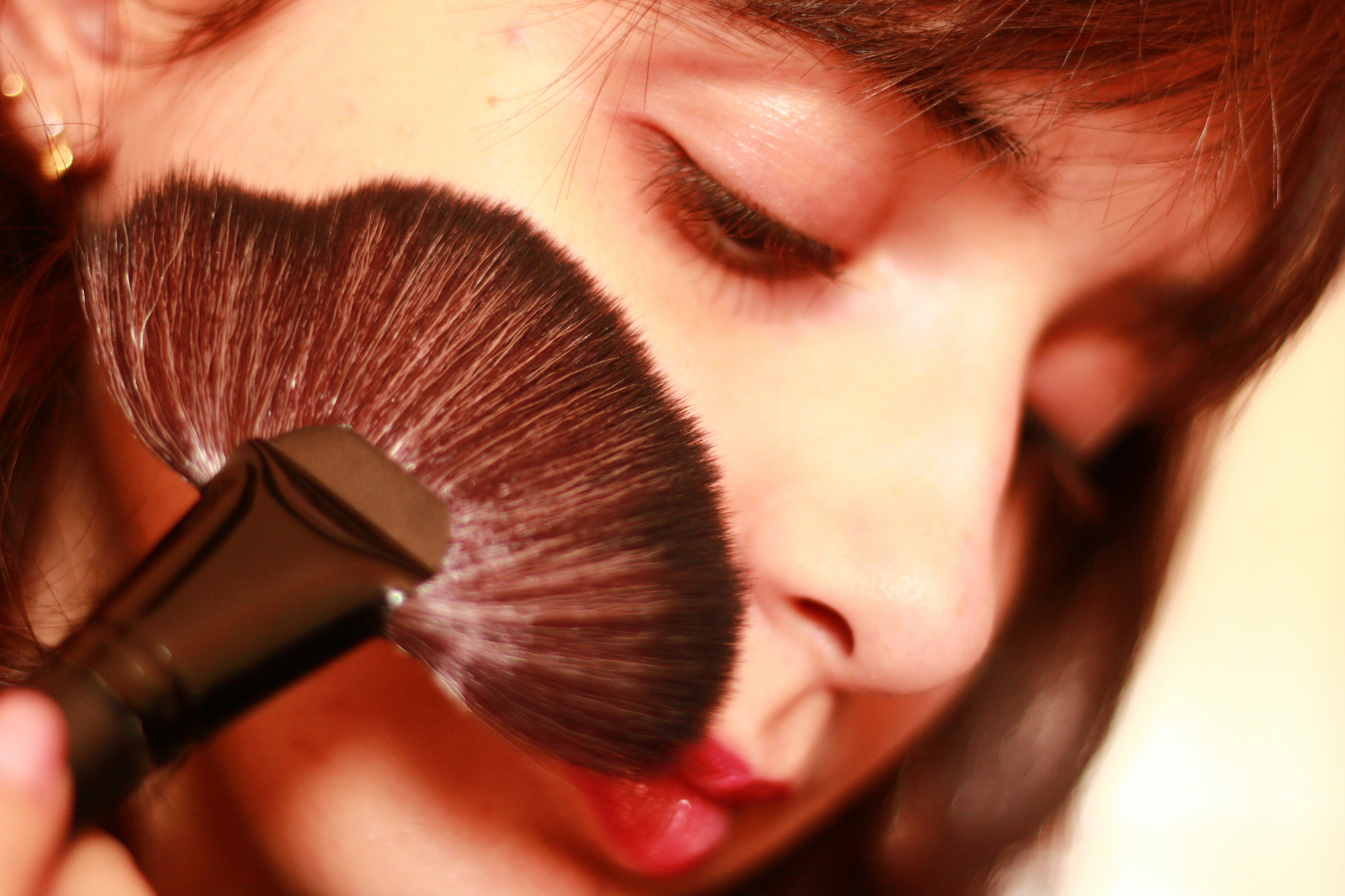 Close-up portrait of a woman brushing product onto her face