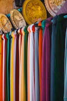 A rack of different colored shirts hanging on a wall