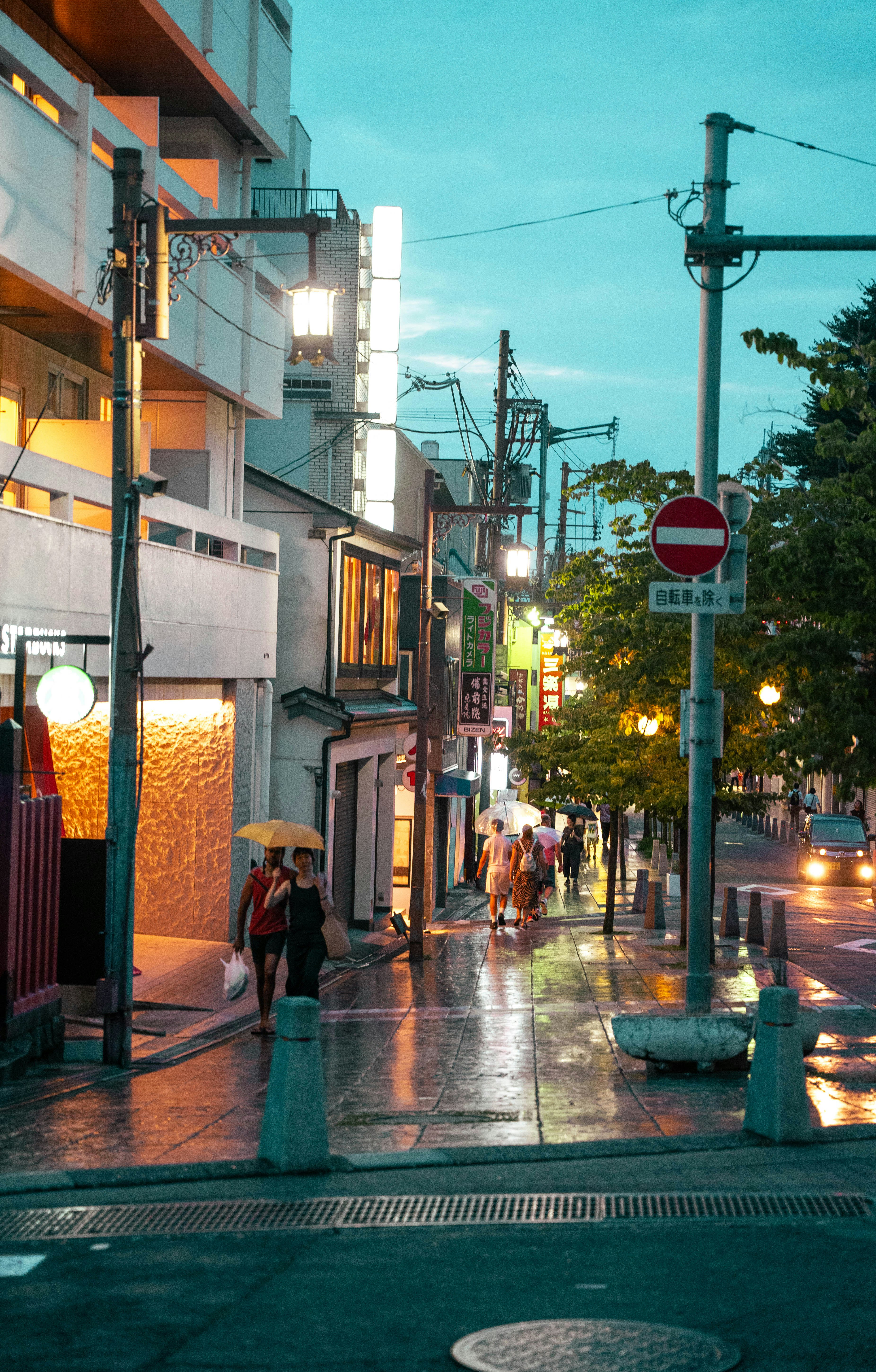 A couple of people walking down a street next to tall buildings