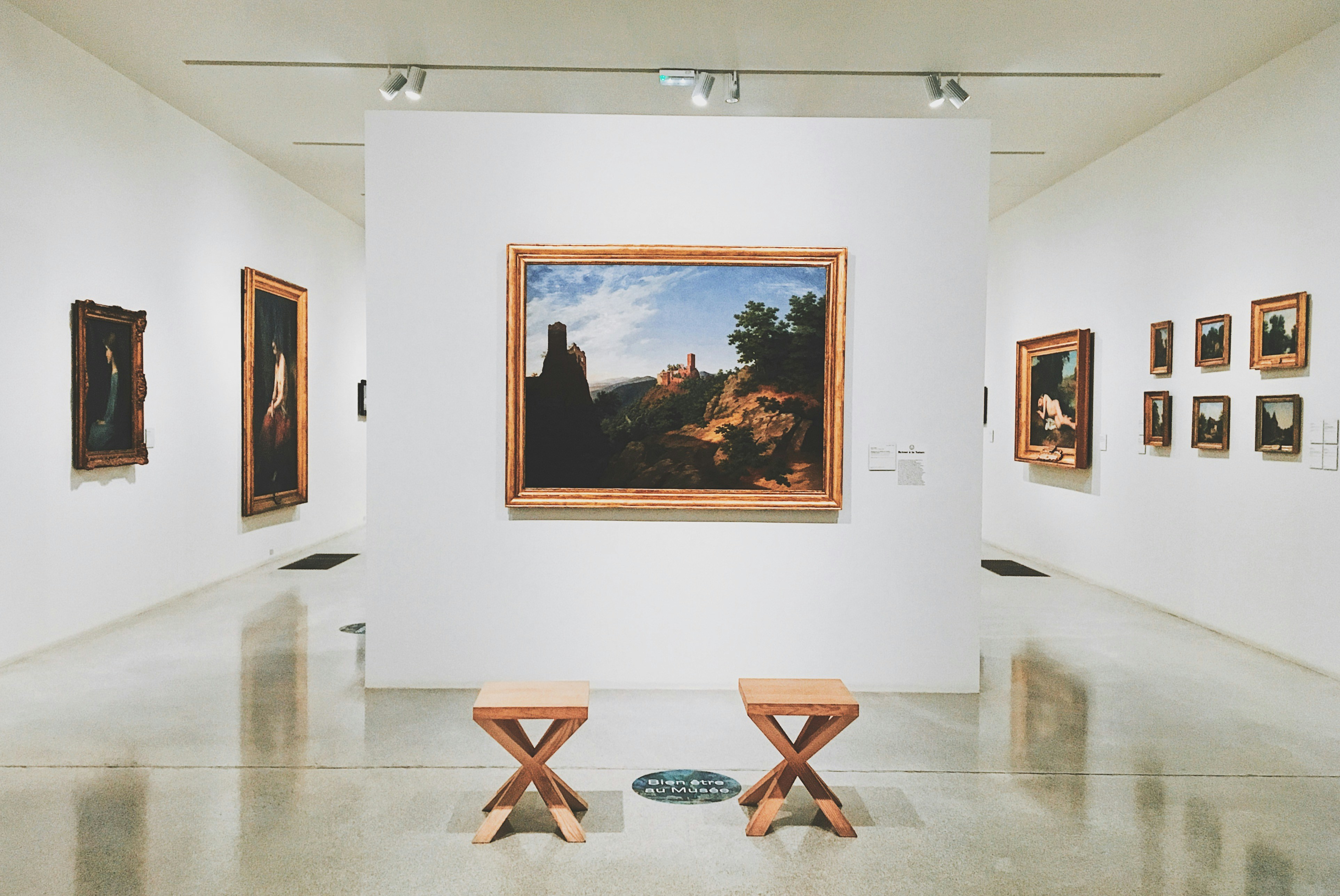 A room filled with lots of paintings and benches