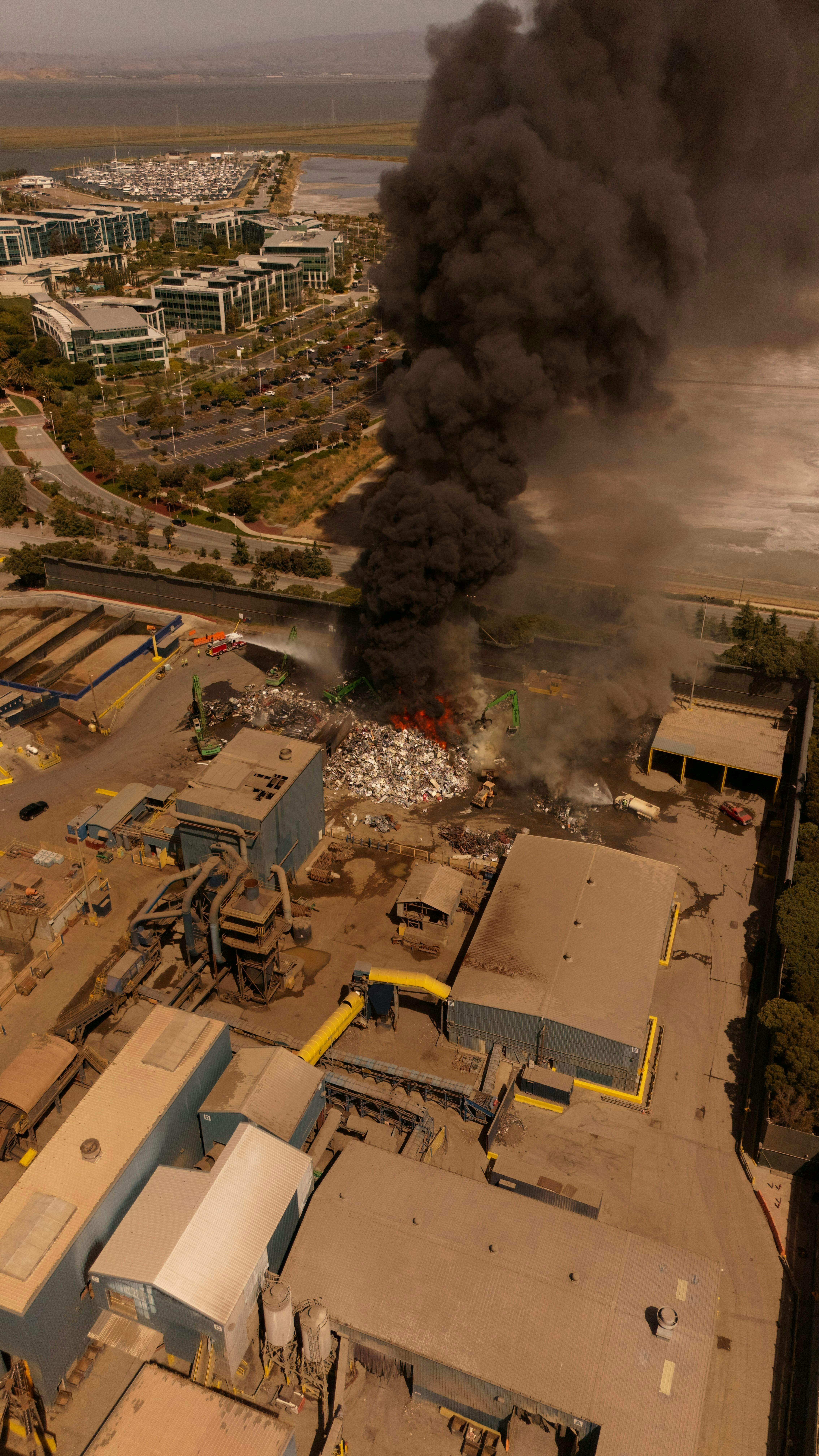 A large black cloud of smoke is billowing out of a factory