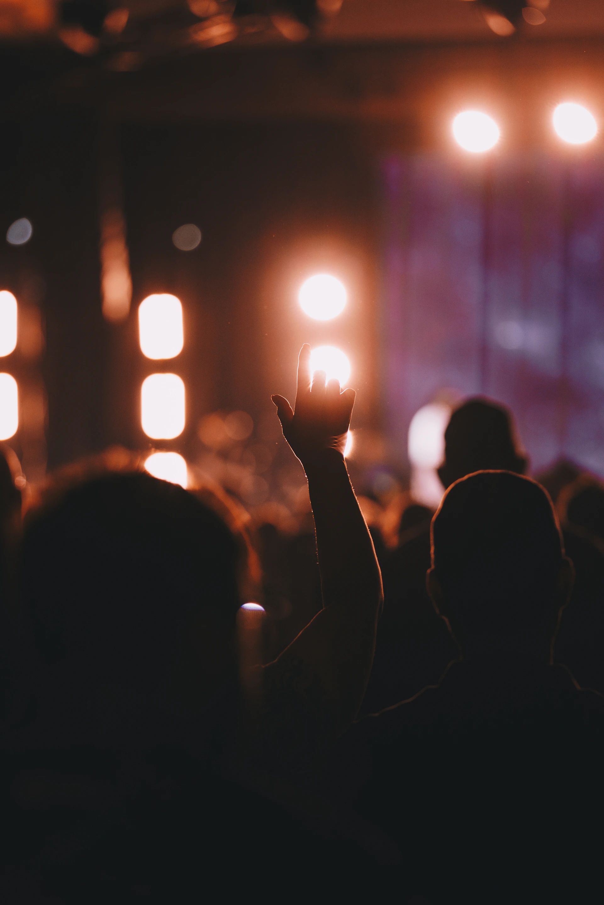 A crowd of people at a concert with their hands in the air