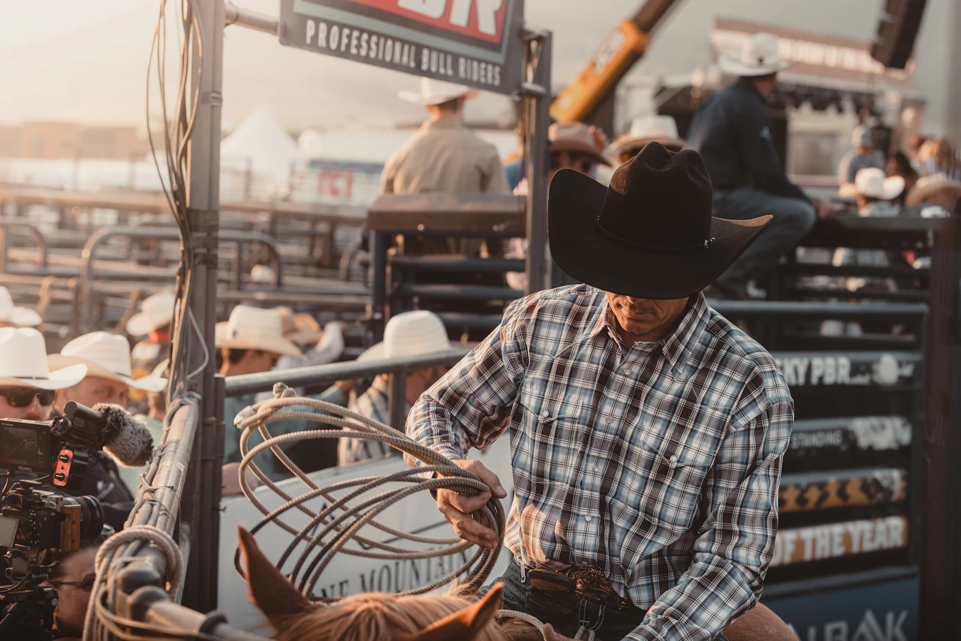 Rancher in a plaid shirt and cowboy hat beside his horse