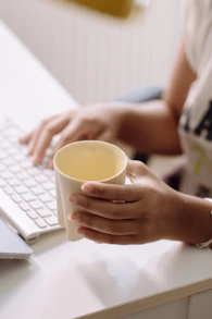 A woman sitting at a desk with a cup of coffee in front of a laptop