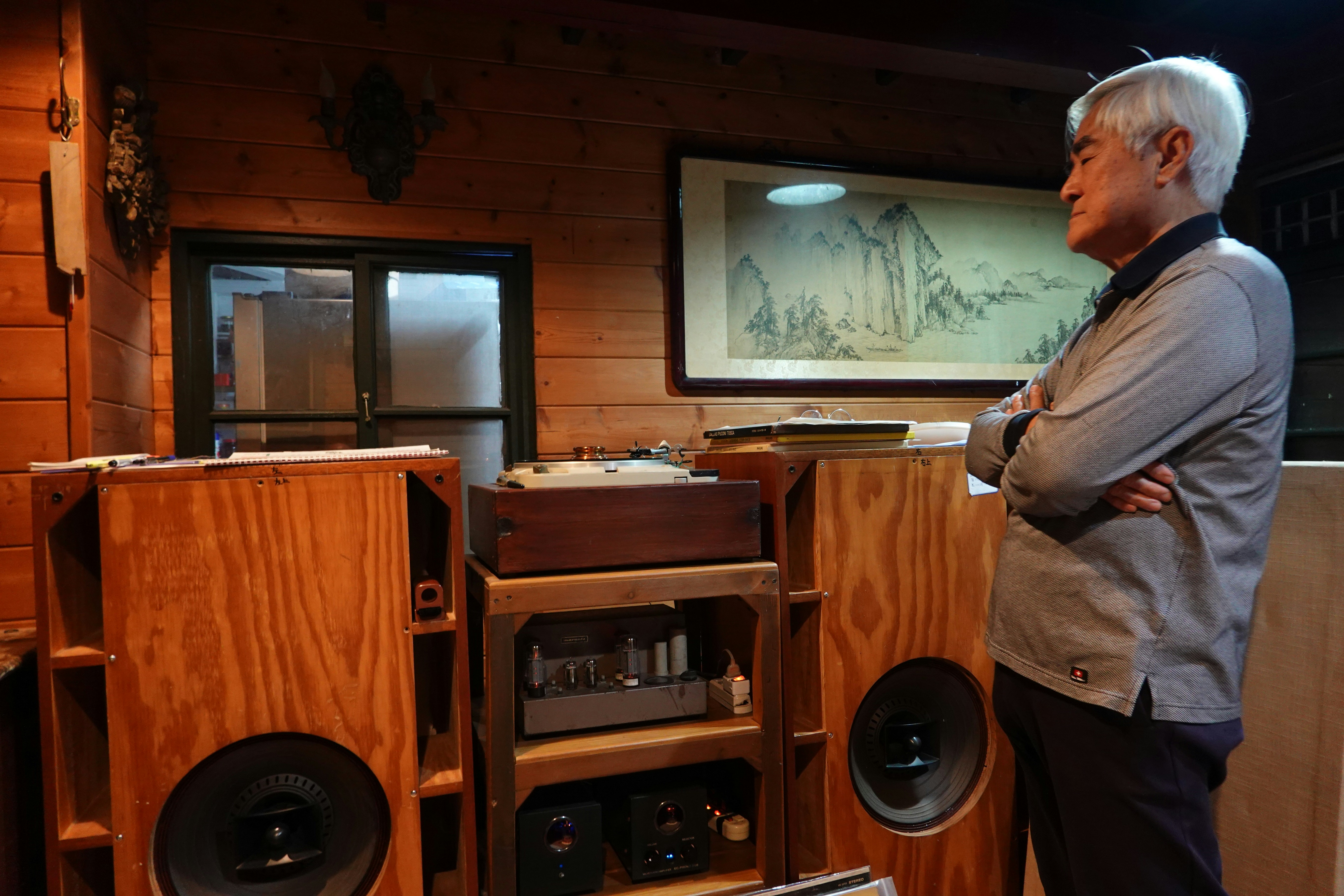 A man standing in a room next to speakers