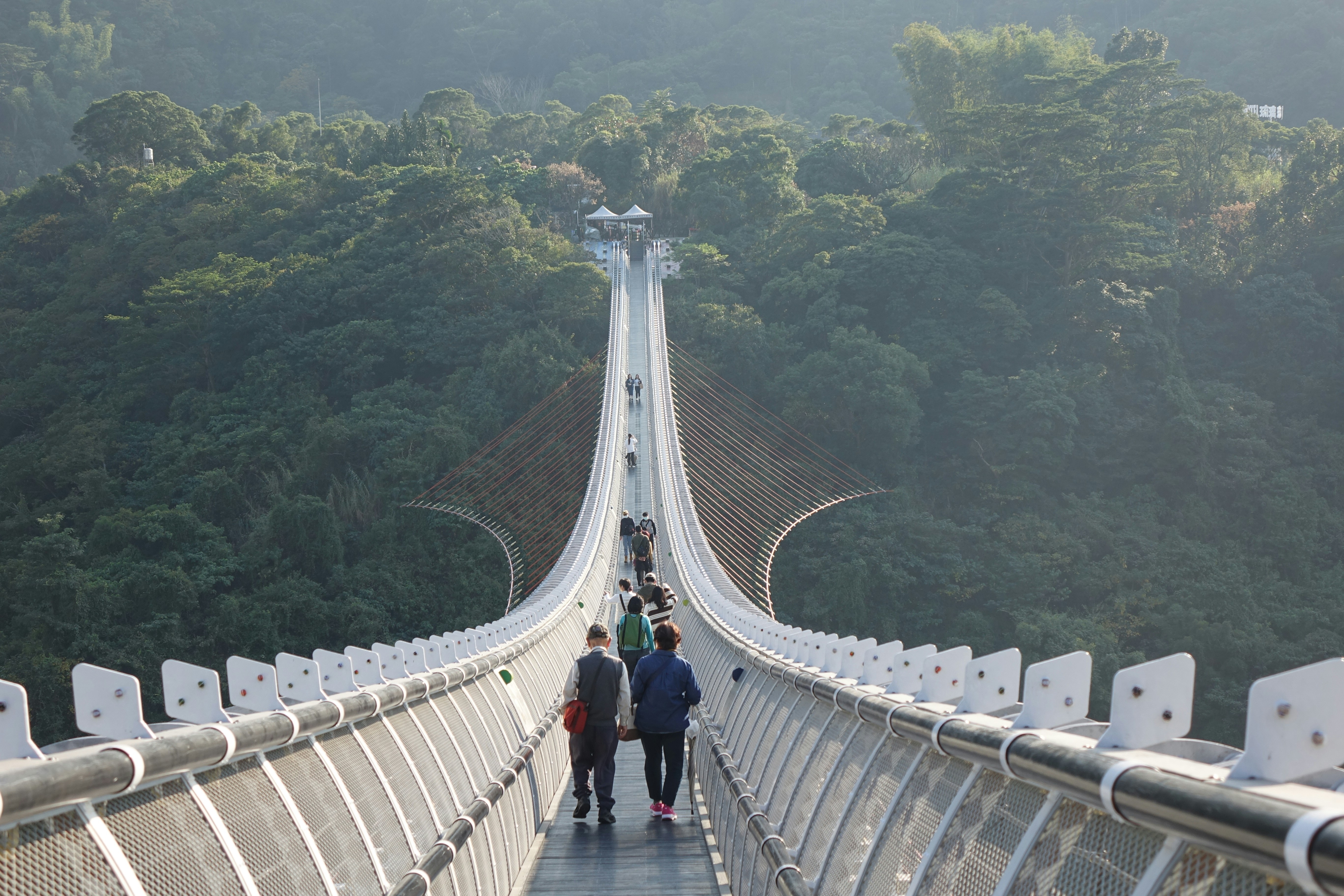 A group of people walking across a suspension bridge