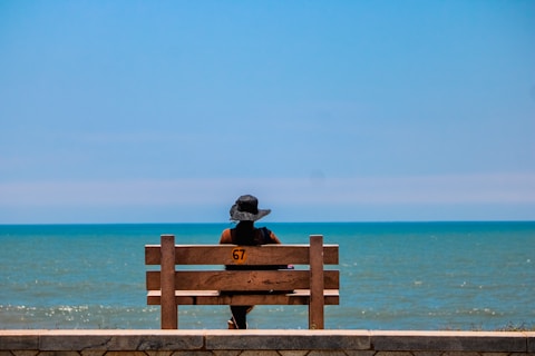 A person sitting on a bench looking out at the ocean
