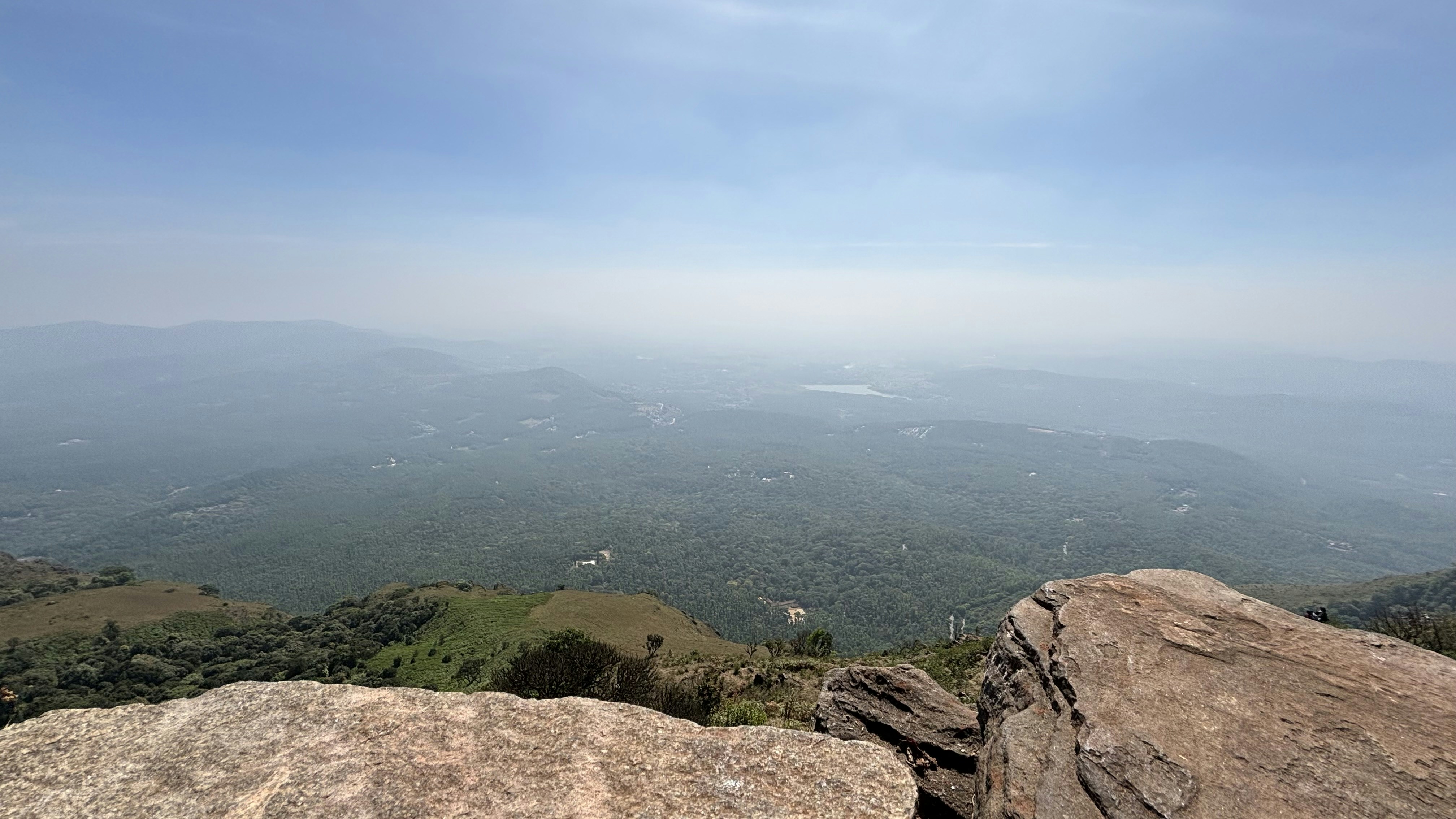 Green Andean valley panorama from mountain viewpoint, bright open sky, rolling hills and mist