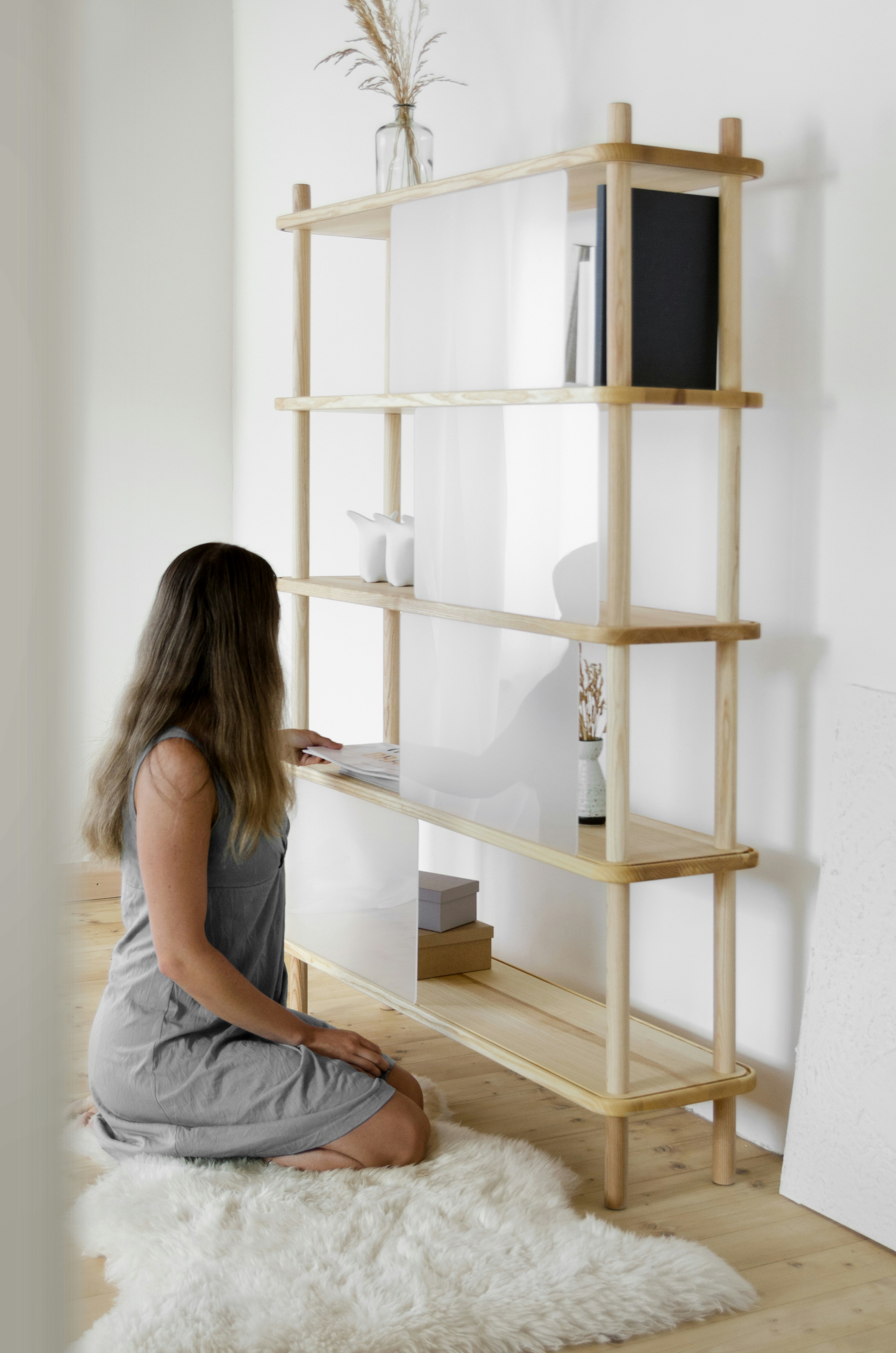A woman sitting on the floor in front of a book shelf