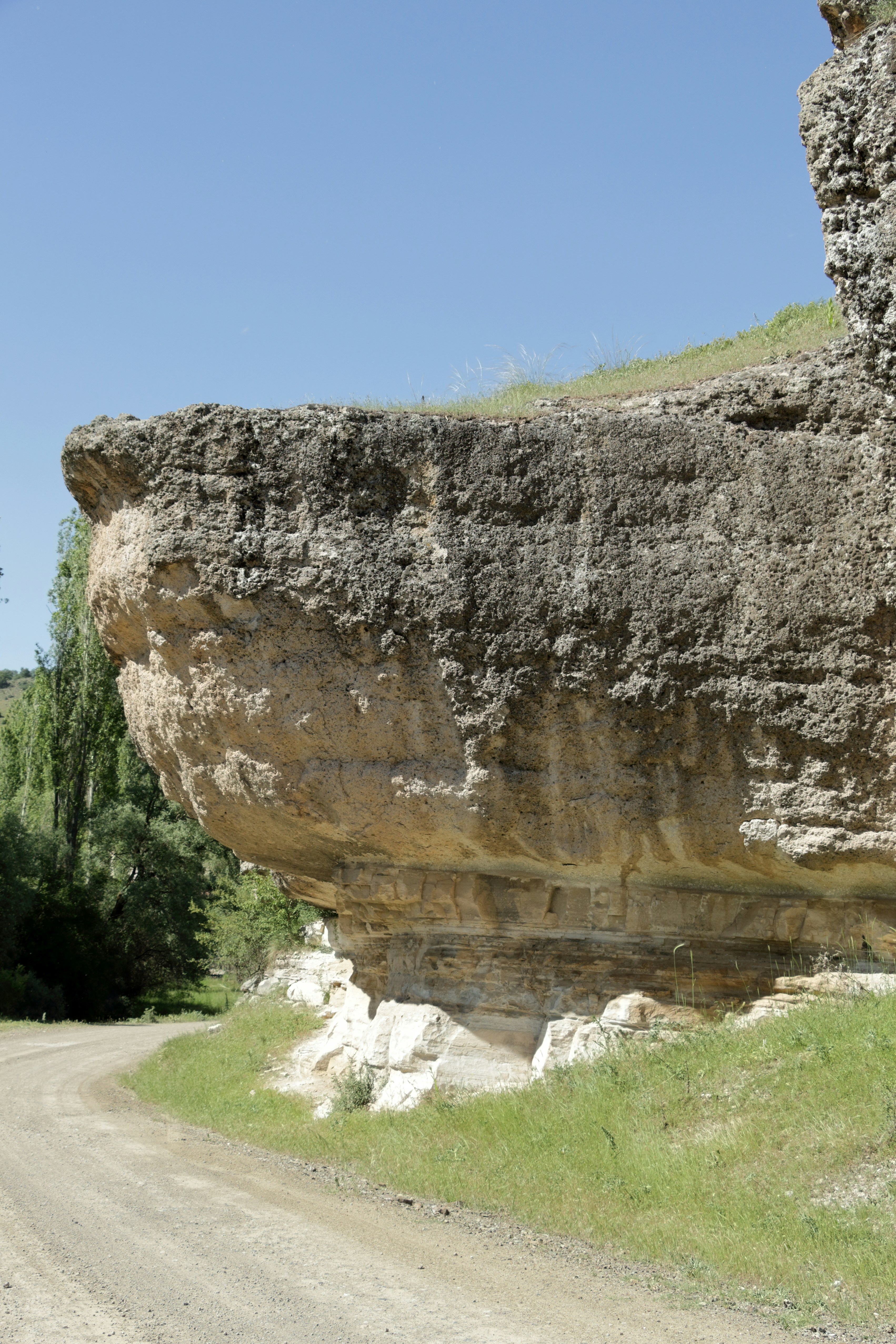 Uma grande rocha sentada ao lado de uma estrada de terra