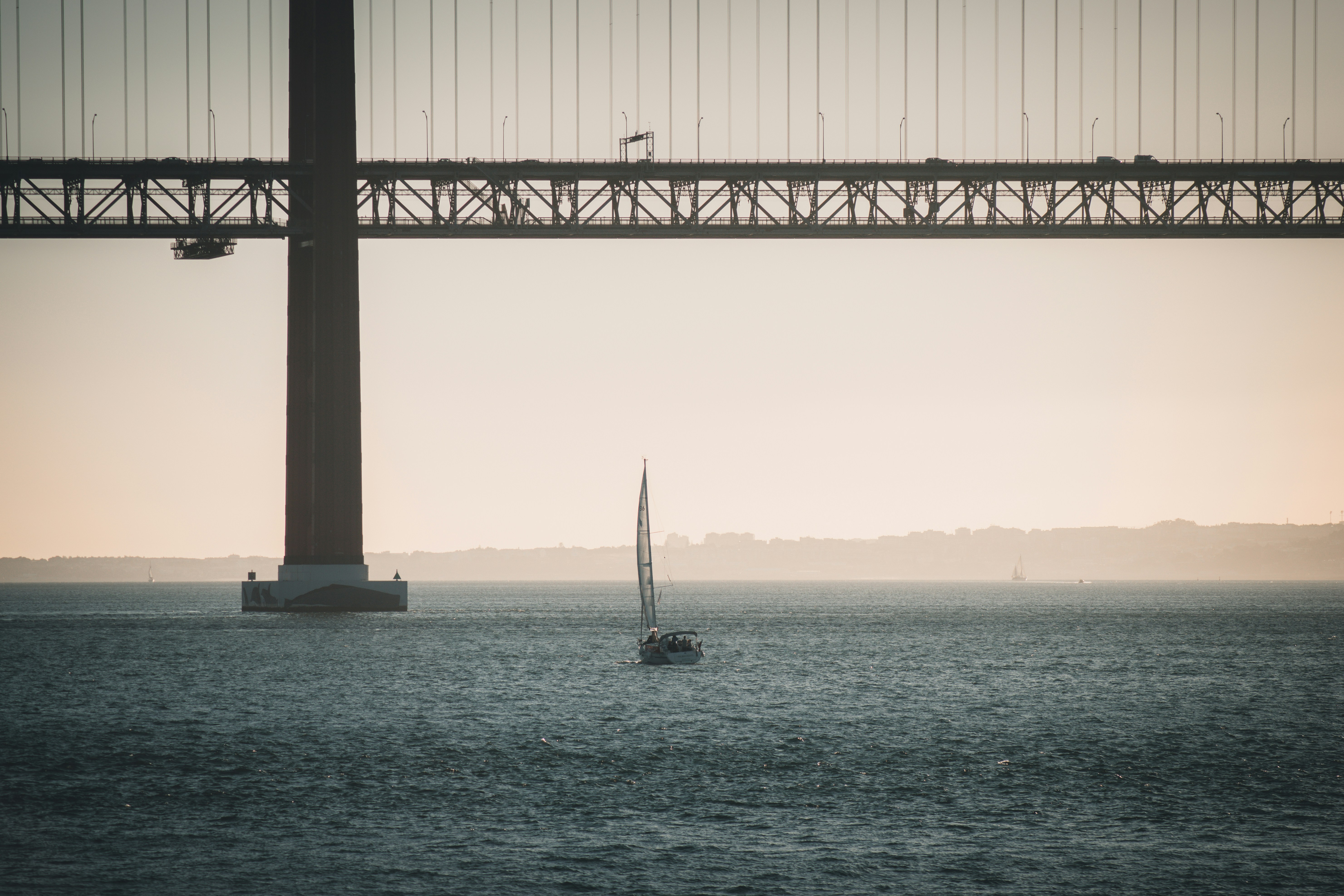 A sailboat in the water under a bridge