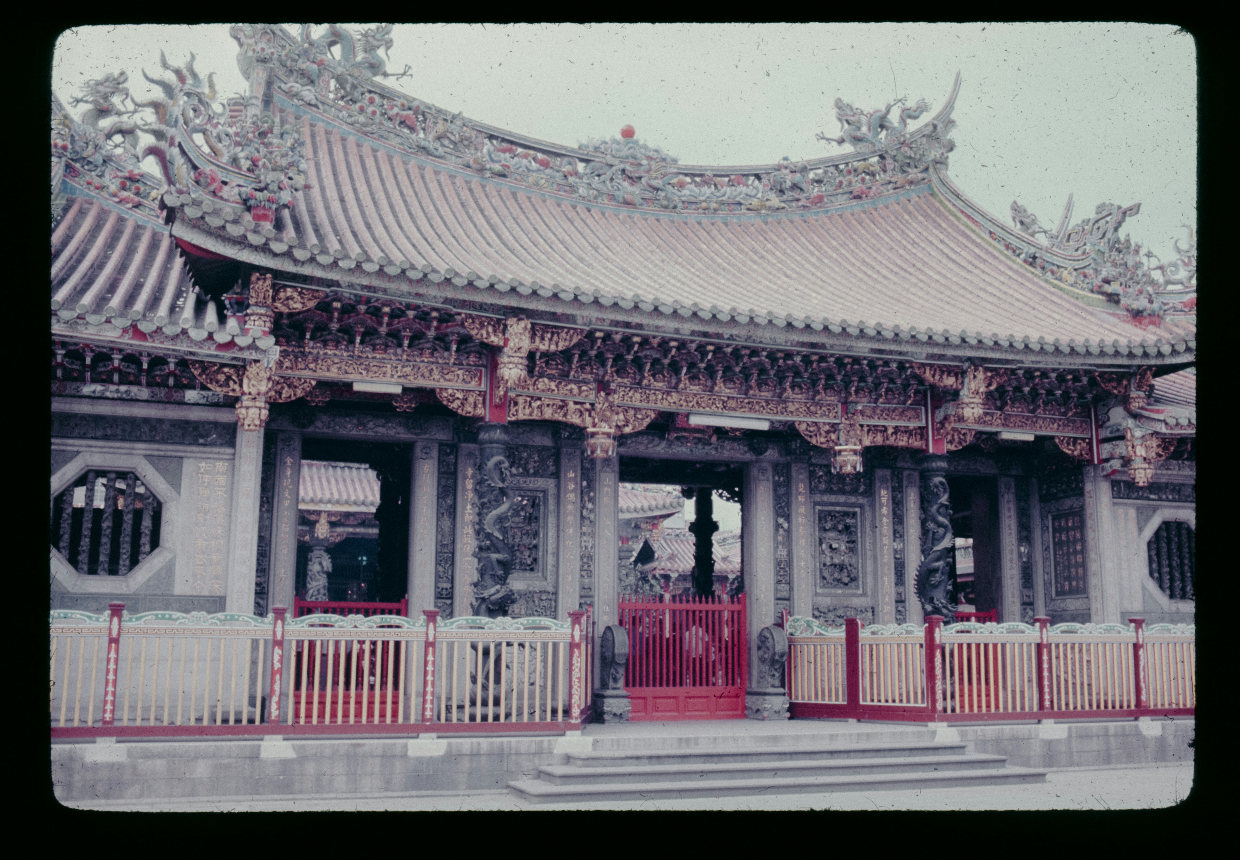 A large building with a red door and a white fence