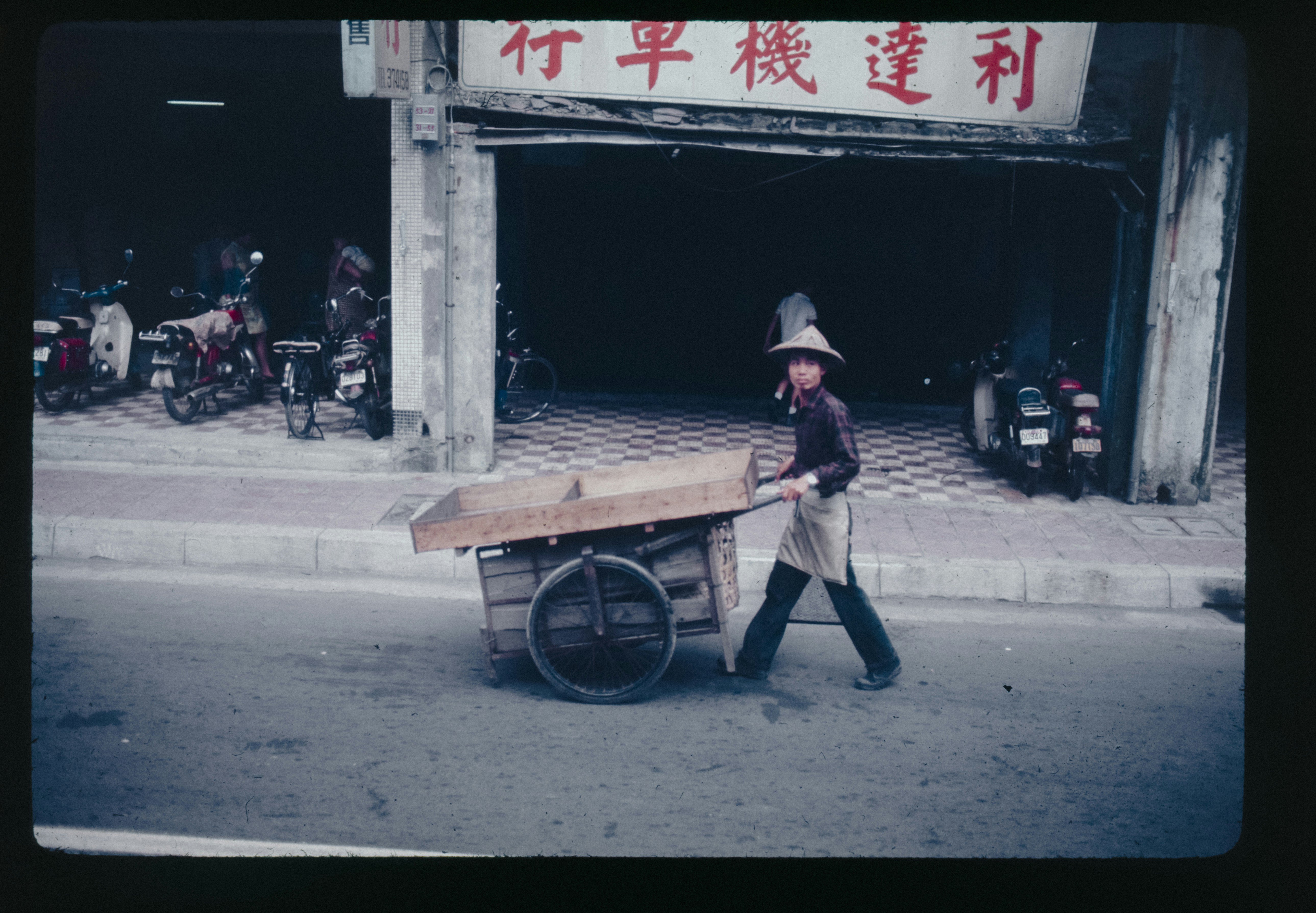 A man pushing a cart down a street