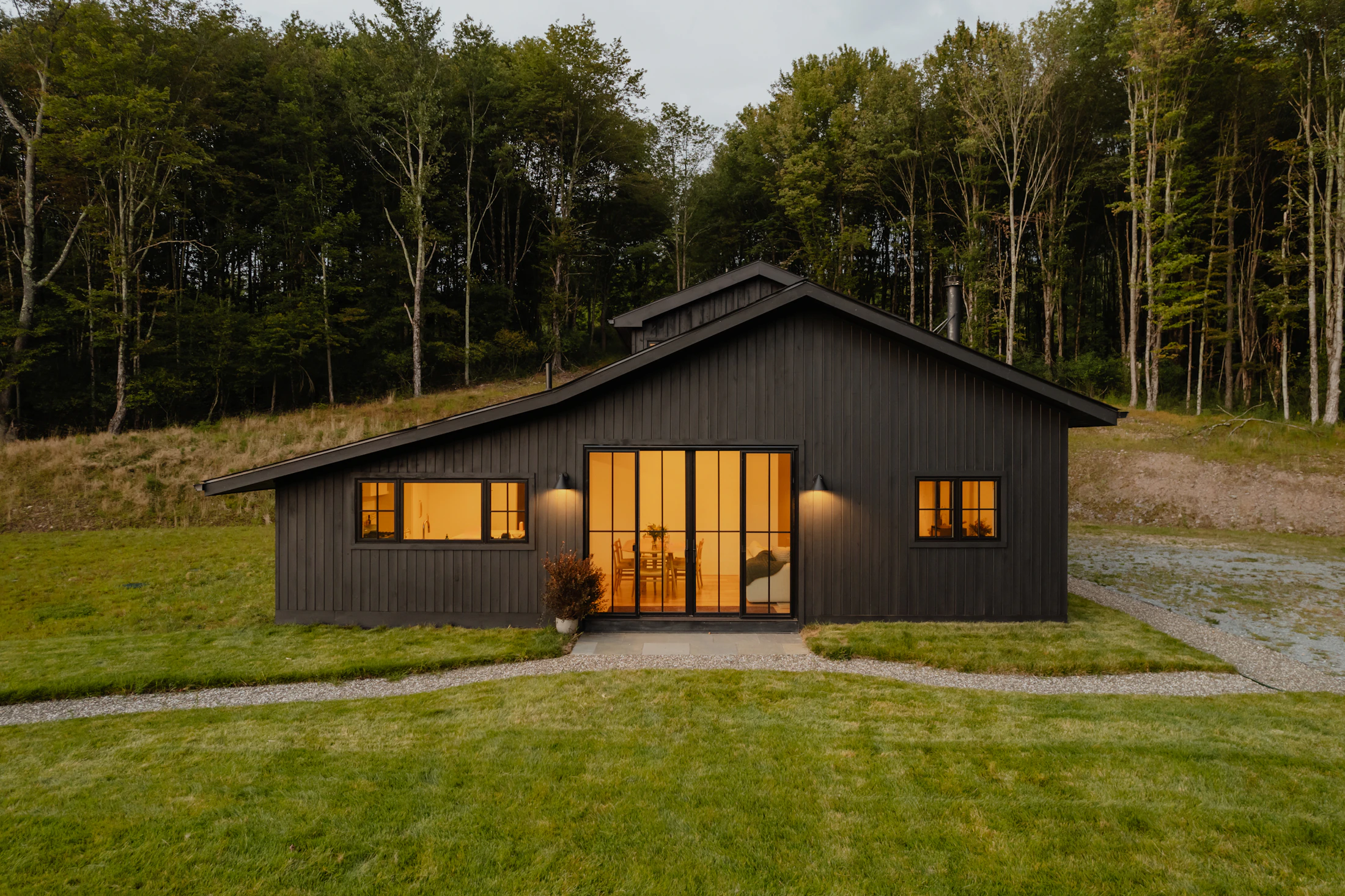 Modern glass prefab cottage with wood exterior and deck surrounded by nature