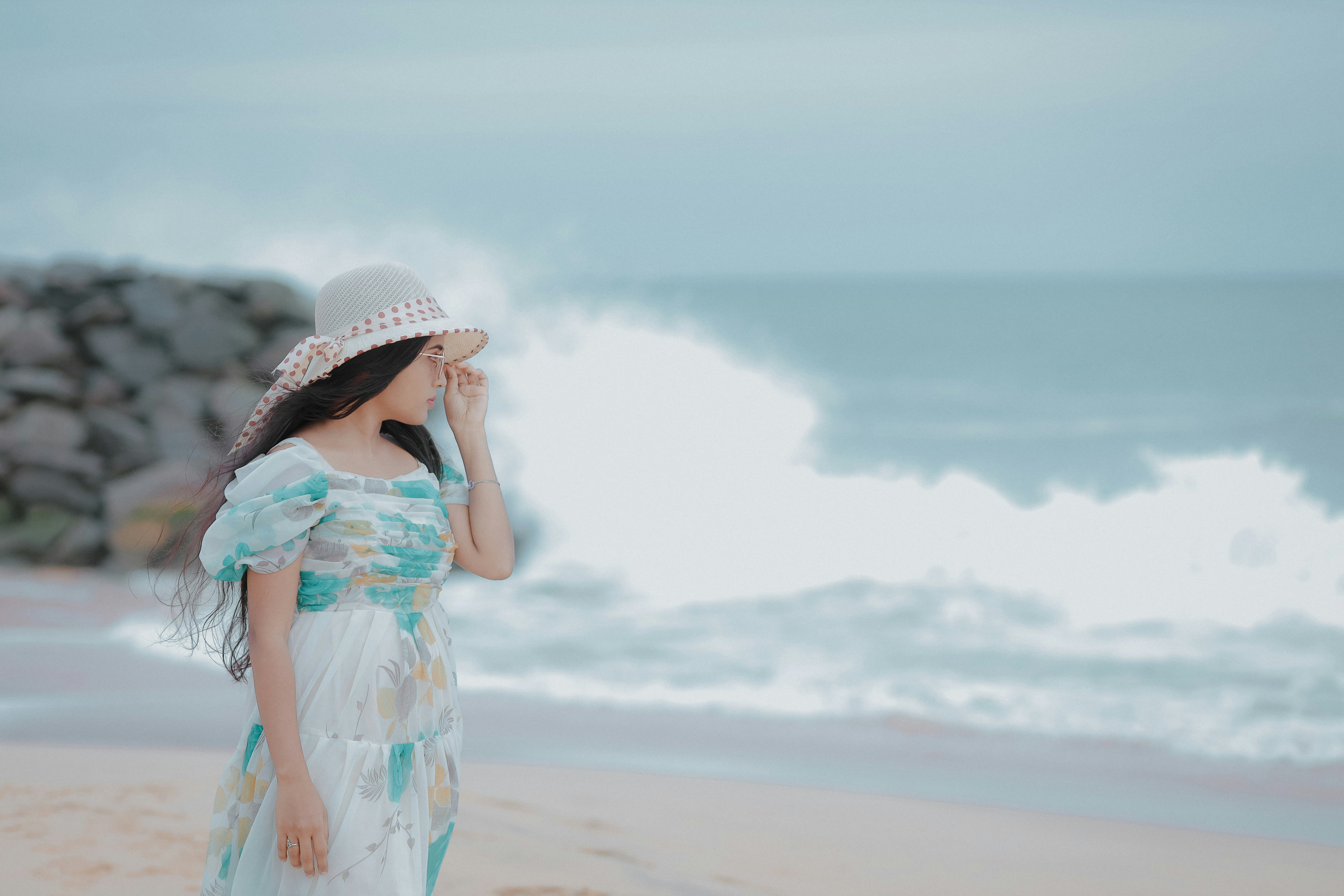 A woman standing on a beach next to the ocean