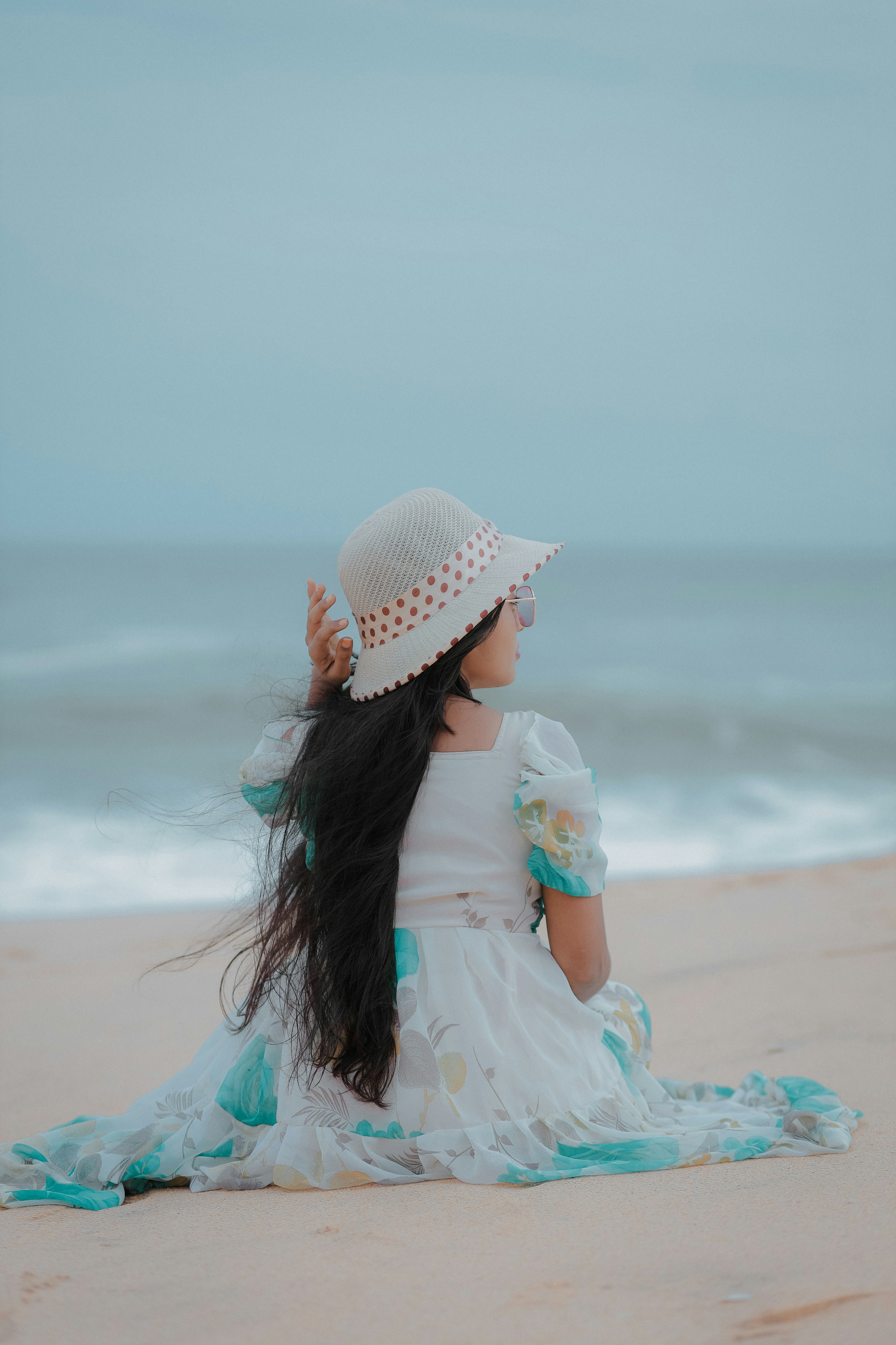 A little girl sitting on top of a sandy beach
