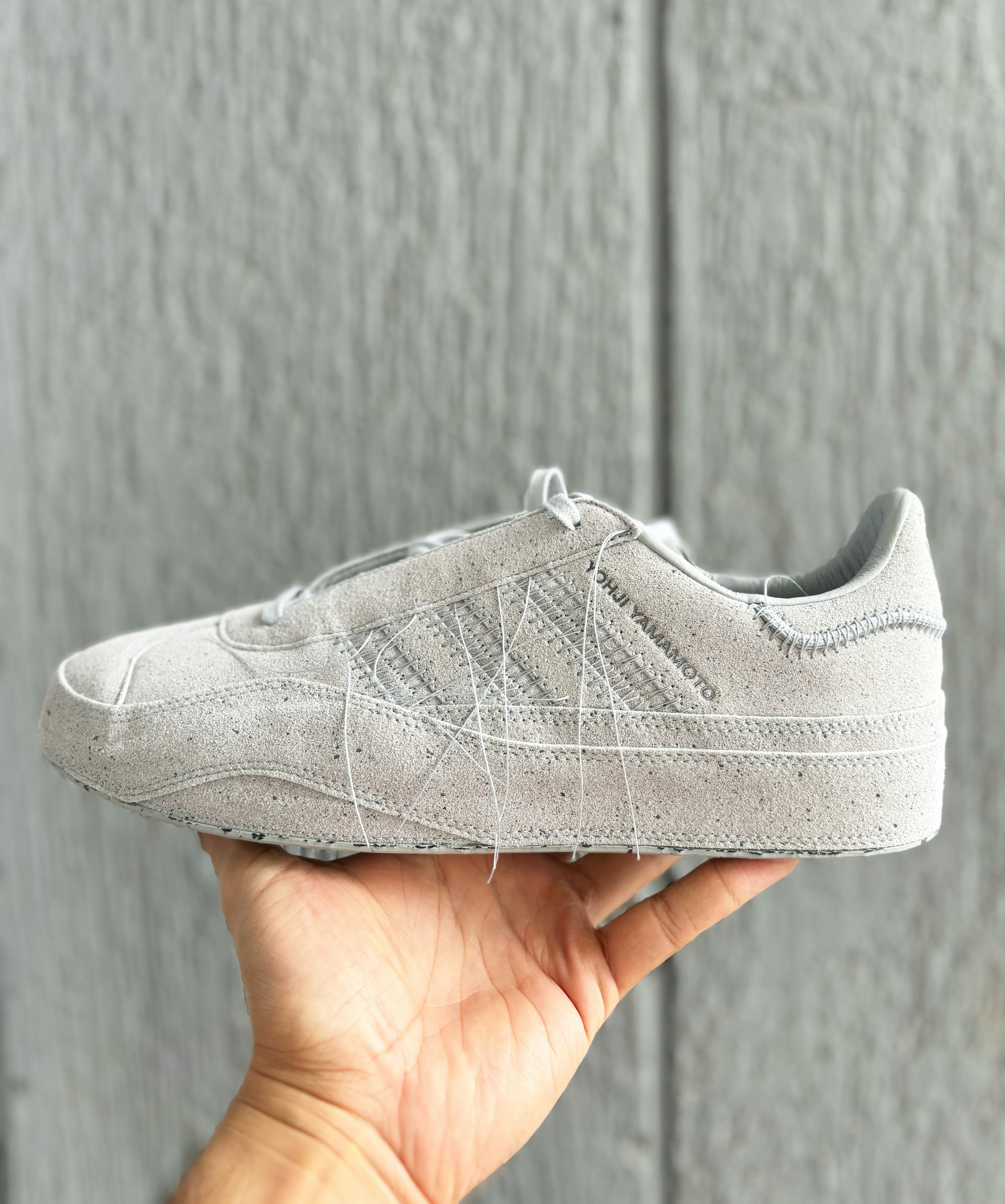 A person holding up a white tennis shoe