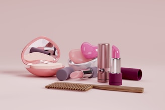 A collection of cosmetics and a comb on a pink background