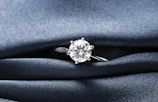 A close up of a diamond ring on a blue cloth