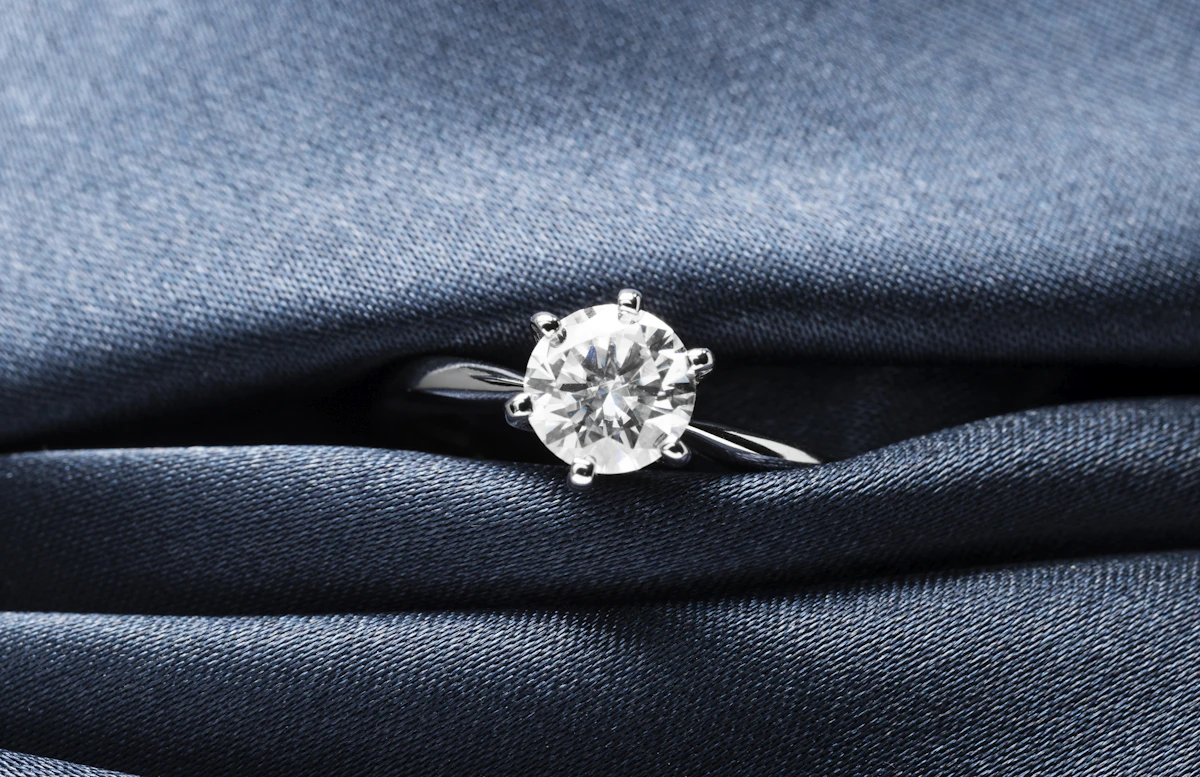 A close up of a diamond ring on a blue cloth