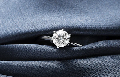 A close up of a diamond ring on a blue cloth