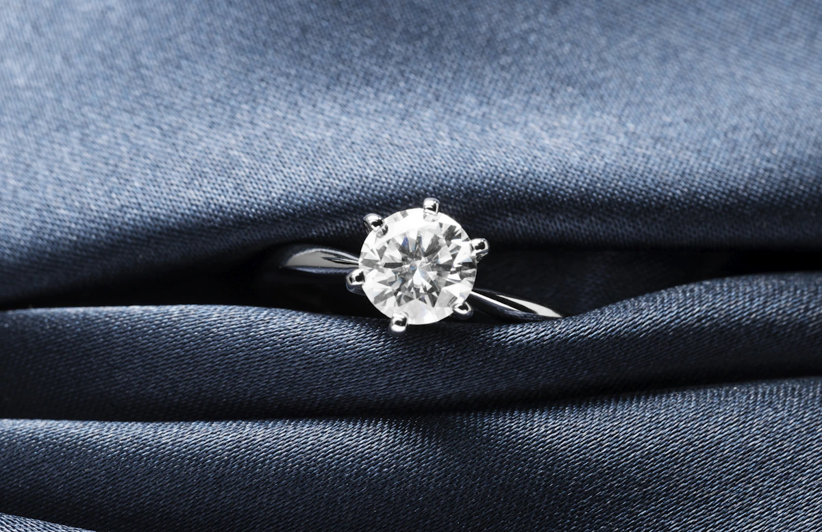 Close-up of a round brilliant diamond ring on blue fabric