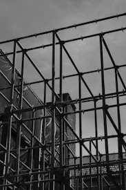 A black and white photo of a building behind a fence