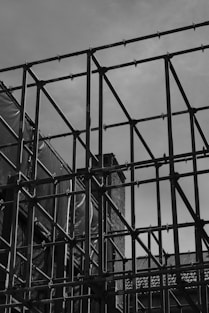 A black and white photo of a building behind a fence