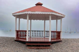 A red and white gazebo sitting on top of a sandy beach