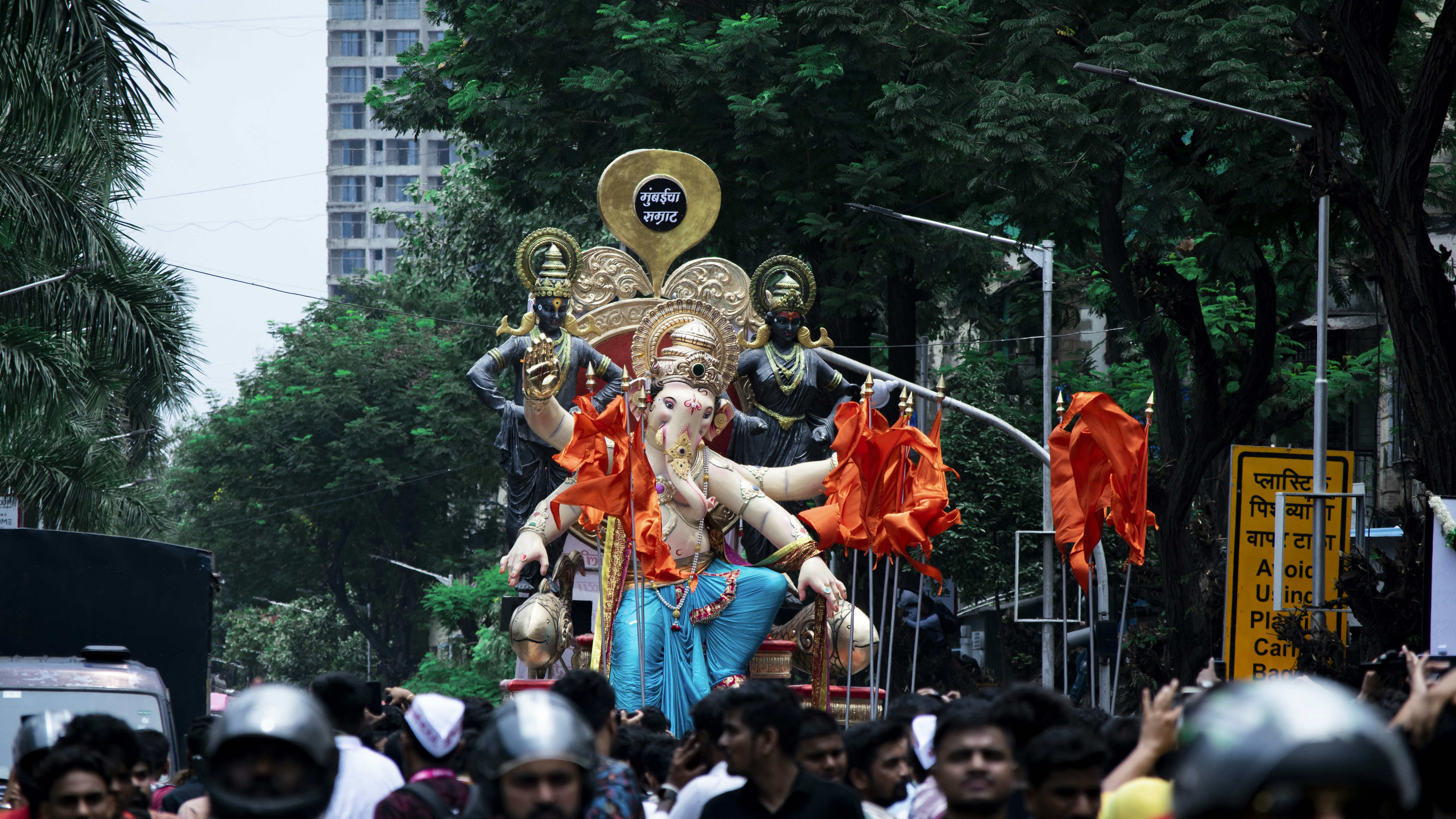 Eine Menschenmenge, die neben einer Statue eine Straße entlang geht