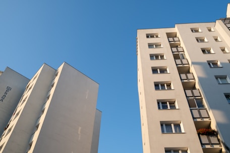 Two tall buildings with balconies against a blue sky